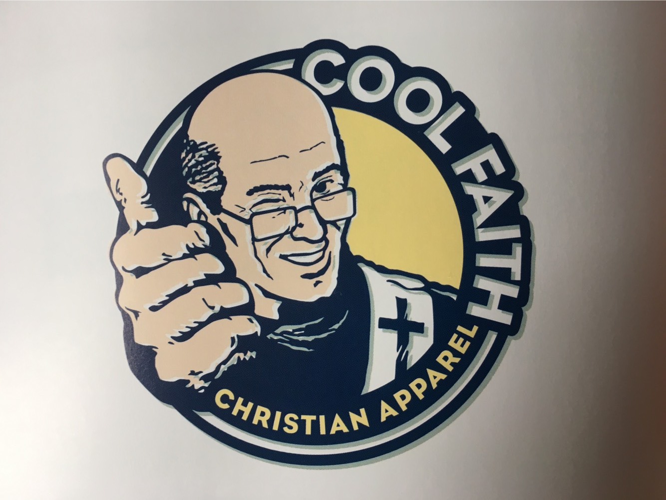 A 2000s-era logo with a winking, balding pastor with reading glasses giving the thumbs up. The name is "Cool Faith: Christian Apparel"